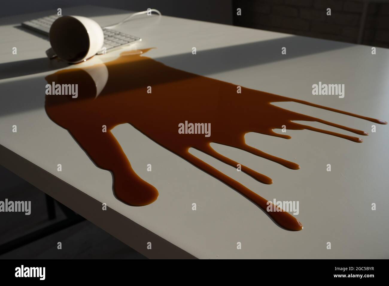Tasse de café noir renversée sur le clavier de l'ordinateur sur la table blanche. Banque D'Images Tasse de café noir renversée sur le clavier de l'ordinateur sur la table blanche. Banque D'Images