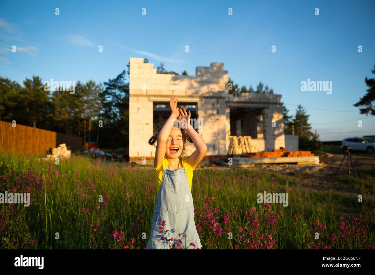 Une petite fille joue et danse près du chantier de construction de sa future maison à la campagne. En attente d'un déménagement, rêves de logements futurs. Mortga Banque D'Images