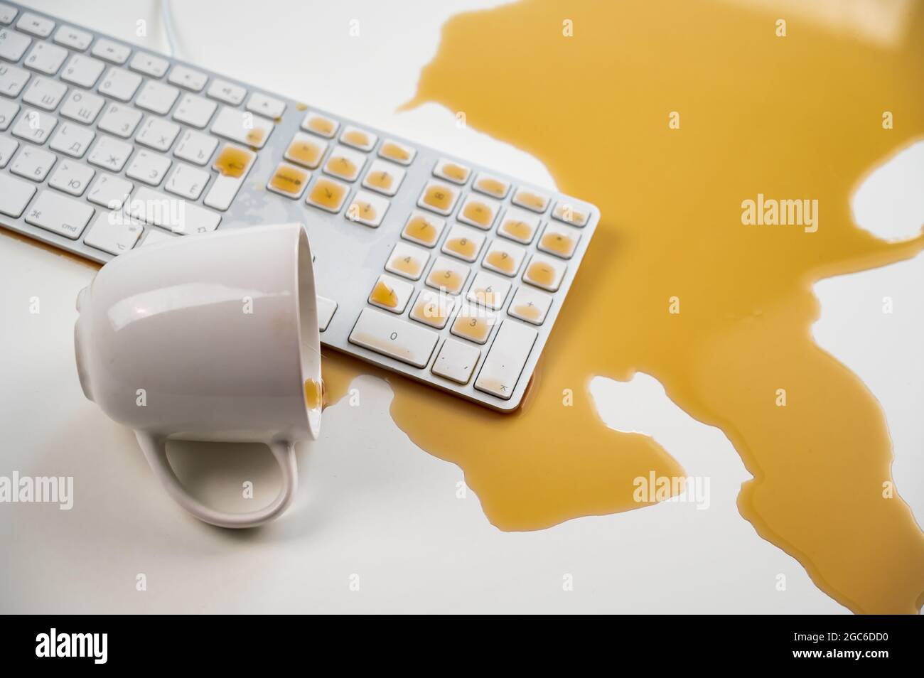 Tasse de café noir renversée sur le clavier de l'ordinateur sur la table blanche. Banque D'Images Tasse de café noir renversée sur le clavier de l'ordinateur sur la table blanche. Banque D'Images