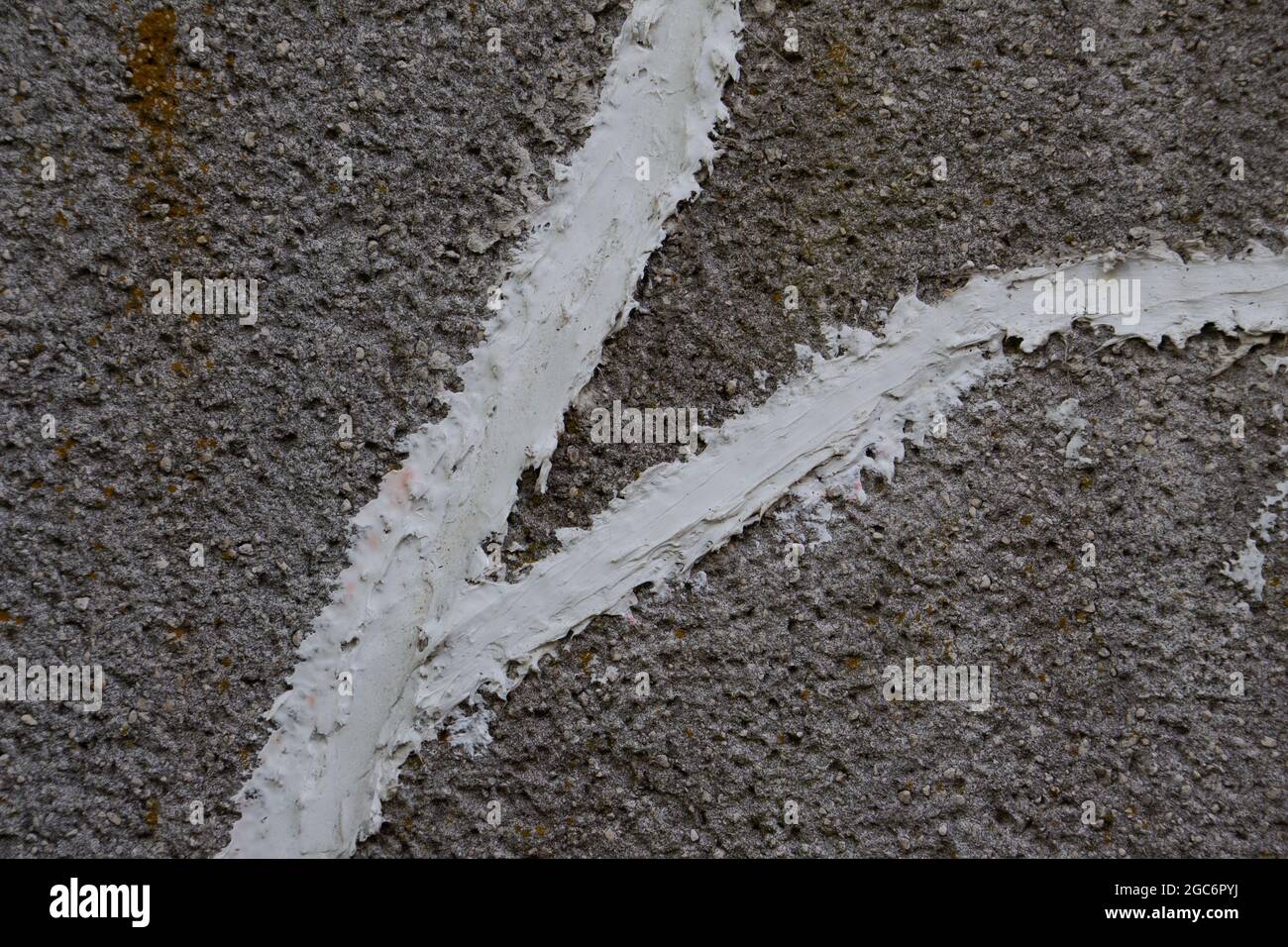 Mur de béton avec courant le long des fissures réparées avec du mastic de correctifs en béton blanc Banque D'Images