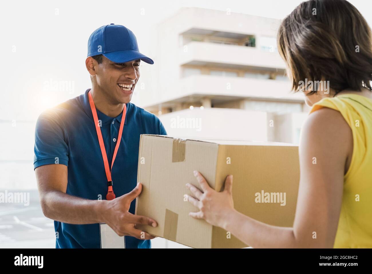 Hispanic courier homme d'expédition carton au client pour la livraison rapide - livreur donnant la commande de paquet à la femme de client - Focus sur Guy f Banque D'Images