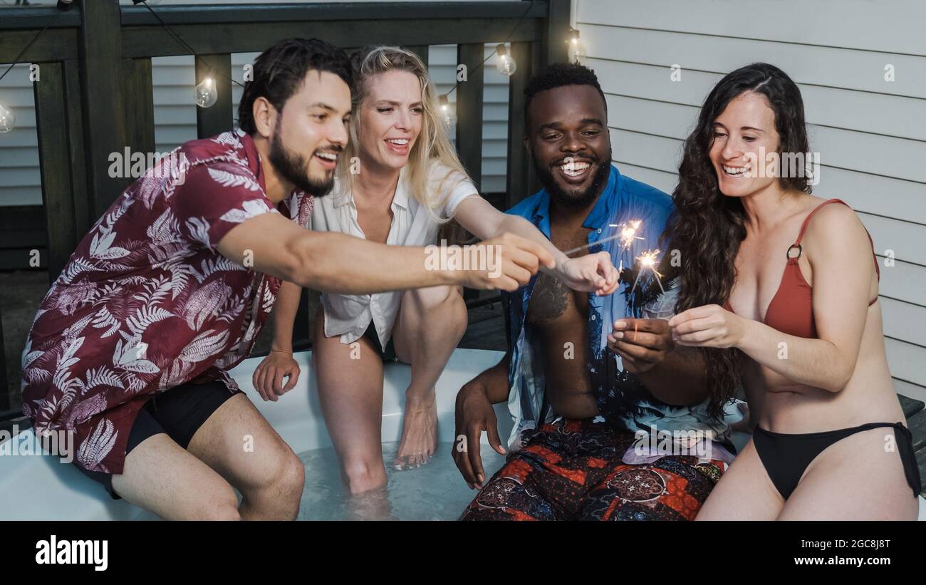 Jeunes gens divers célébrant avec des sparklers dans le jacuzzi de luxe à l'hôtel de villa - foyer principal sur le visage de l'homme afro-américain Banque D'Images