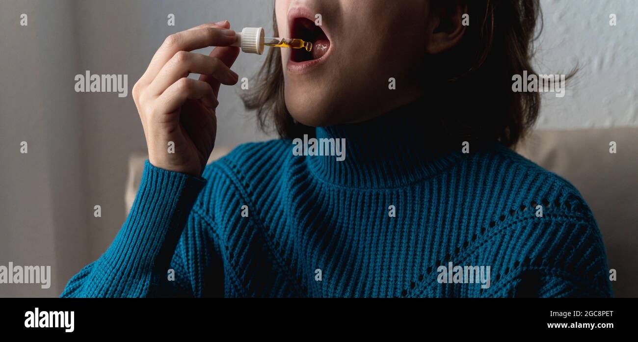 Femme prenant l'huile de cbd sous la langue - concept de médecine alternative - Focus sur le compte-gouttes Banque D'Images