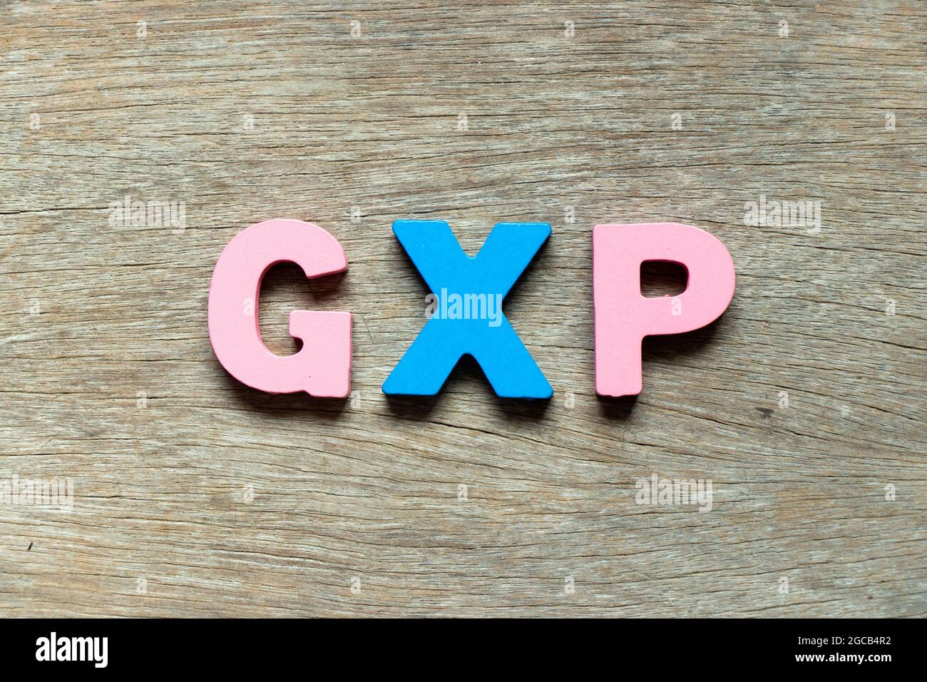 Lettre de couleur dans le mot GXP sur fond de bois Banque D'Images