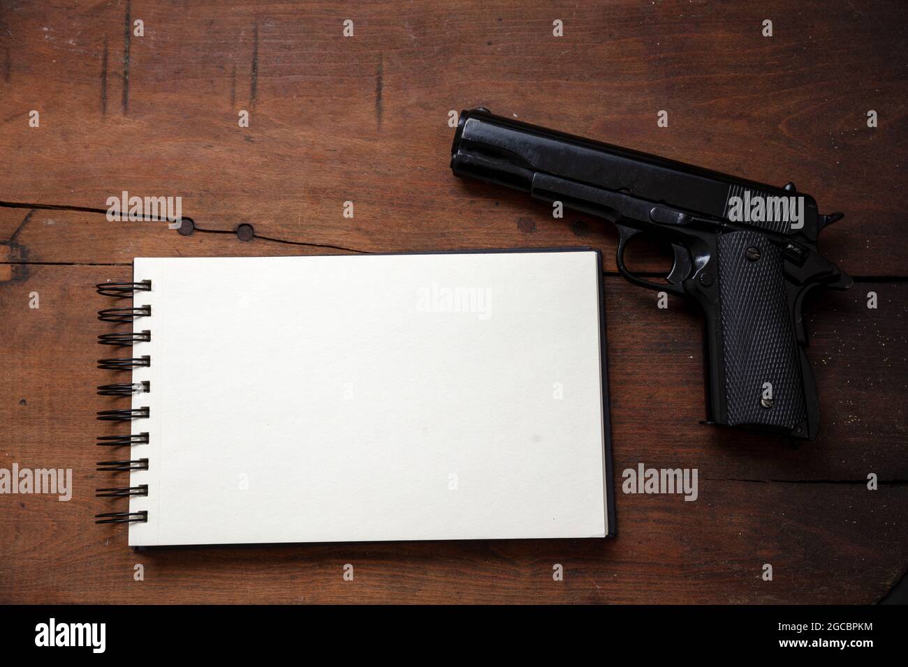 Note de suicide, concept de liste noire. Bloc-notes vierge et pistolet sur fond de table en bois, vue du dessus. Copier le modèle d'espace Banque D'Images