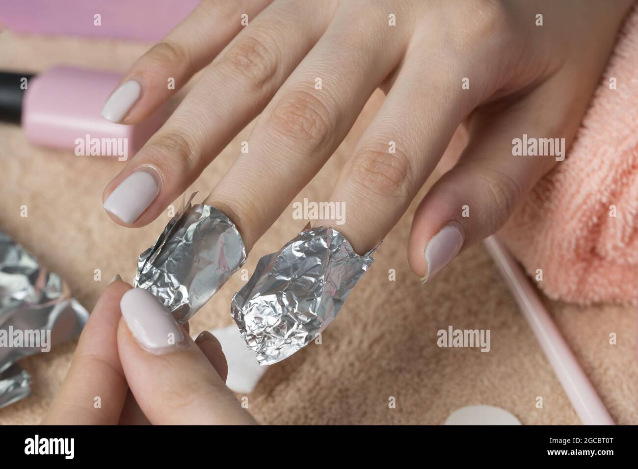 Retirez le produit à polir à base de gel avec du papier d'aluminium. La femme verse le liquide sur un tampon de coton, le met sur un clou et enveloppe le papier d'aluminium. Retrait des clous en shellac. Faites une manucure Banque D'Images