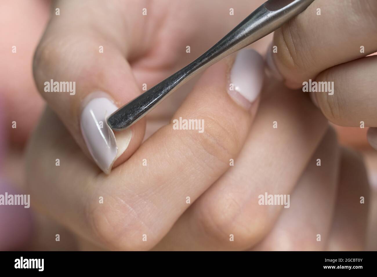 Retirez le produit à polir pour gel à l'aide d'un poussoir métallique. La femme retire le gel lustrant shellac des ongles à l'aide d'un poussoir, manucure à la maison. Retrait du gel polonais de na Banque D'Images