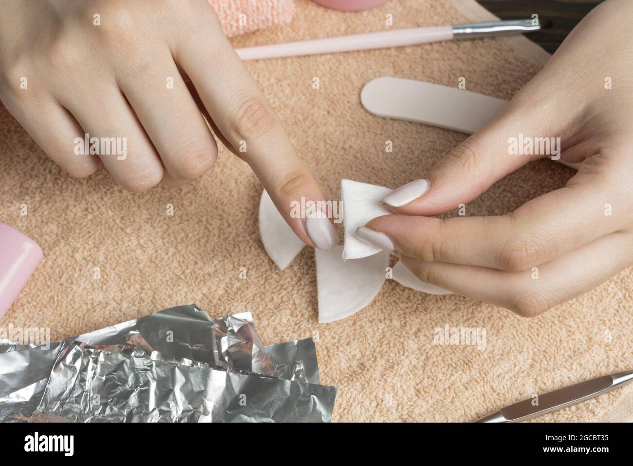 Retirer le gel polonais des ongles. La femme verse le liquide sur un tampon  de coton, le met sur un clou et enveloppe le papier d'aluminium. Retrait  des clous en shellac. Faites