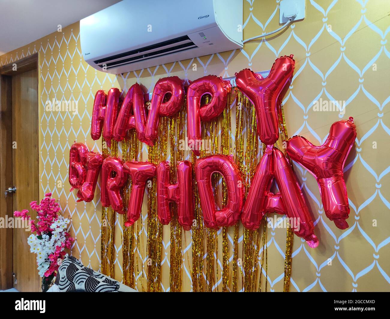 Banderole suspendue à motif ballons d'or joyeux anniversaire sur le mur. Décorations de fête d'anniversaire. Intérieur de la maison. Banque D'Images