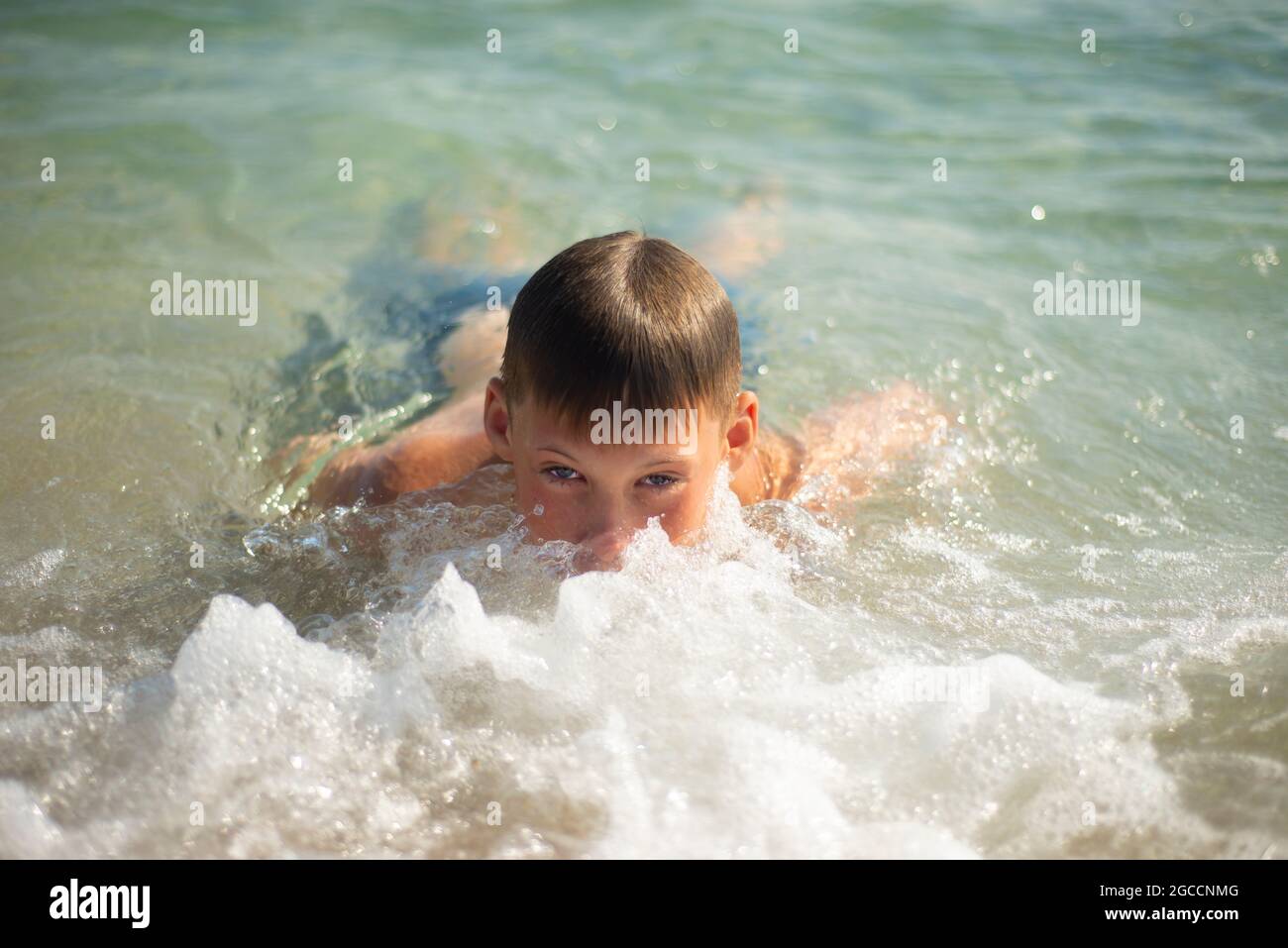 Le garçon nage dans la mer. Face en mousse de mer. Émotions satisfaites. Plaisir Banque D'Images