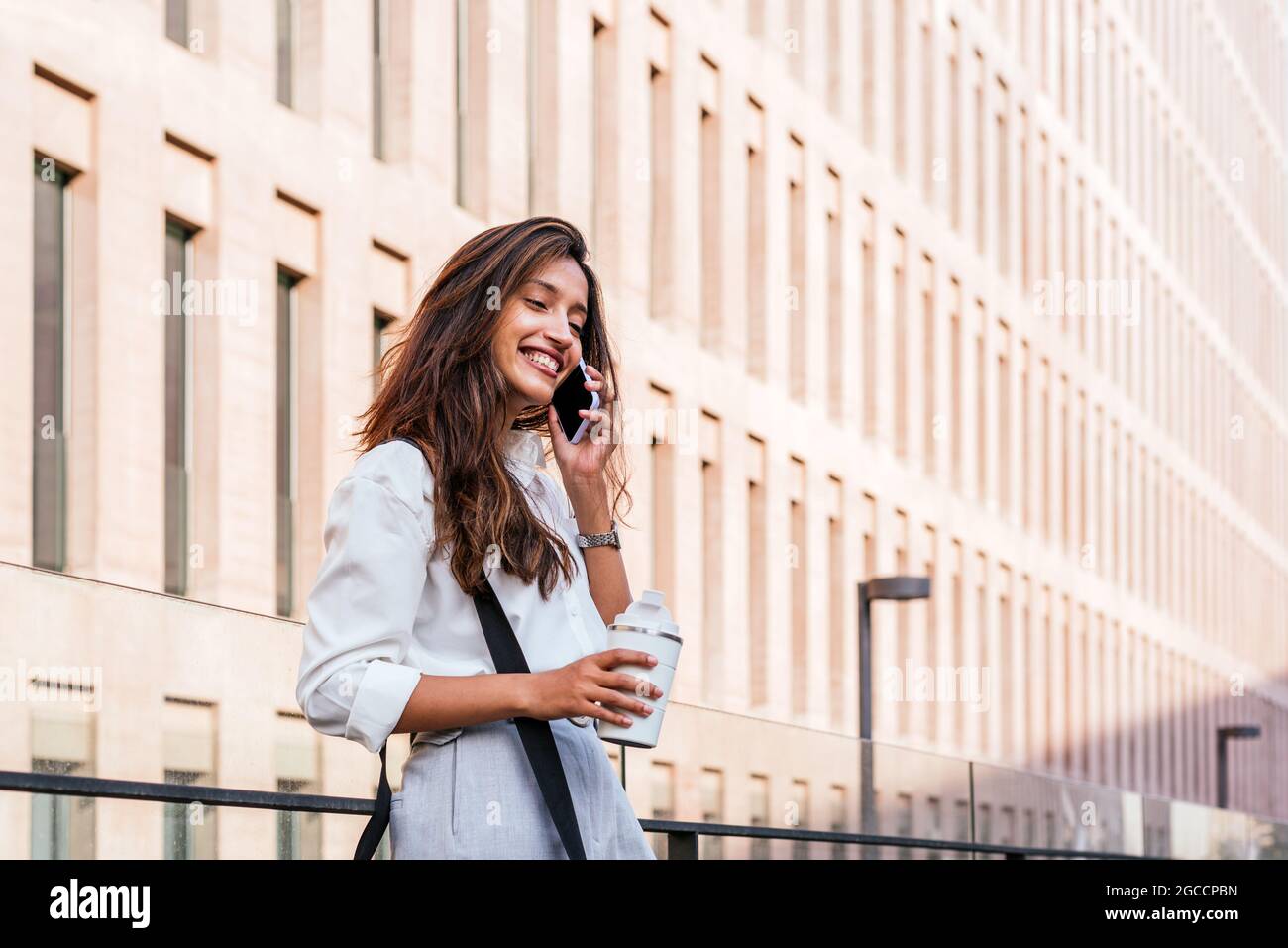 portrait horizontal d'une jeune femme indienne attrayante parlant au téléphone. Elle se trouve près de l'immeuble de bureaux Banque D'Images