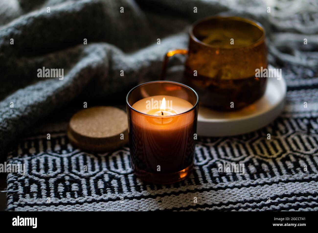 Bougie chaleureuse dans un pot en verre brun, décoration intérieure d'hiver  avec tasse et couverture Photo Stock - Alamy