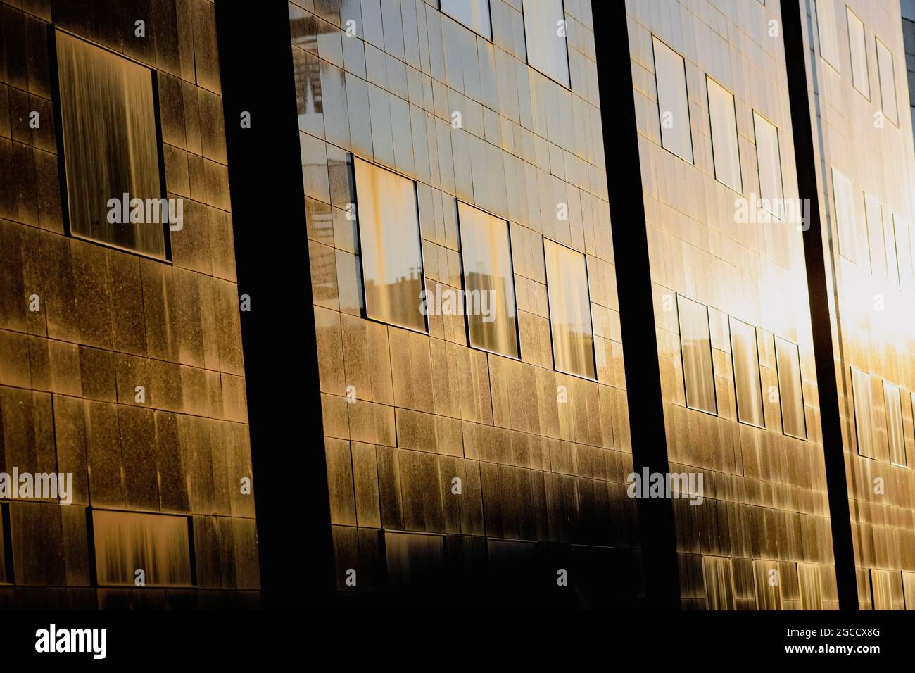 Le soleil couchant se reflète dans les fenêtres d'un grand immeuble de bureaux en verre dans le vieux centre de Bucarest. Banque D'Images