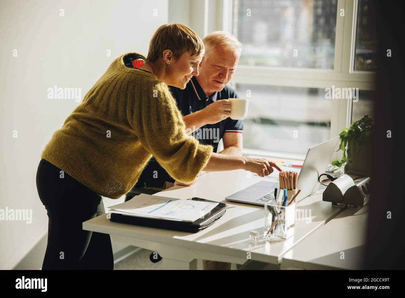 Deux collègues discutent du projet au bureau sur un ordinateur portable. homme d'affaires et femme discutant comme ils regardent un ordinateur portable sur un bureau en face de la Banque D'Images