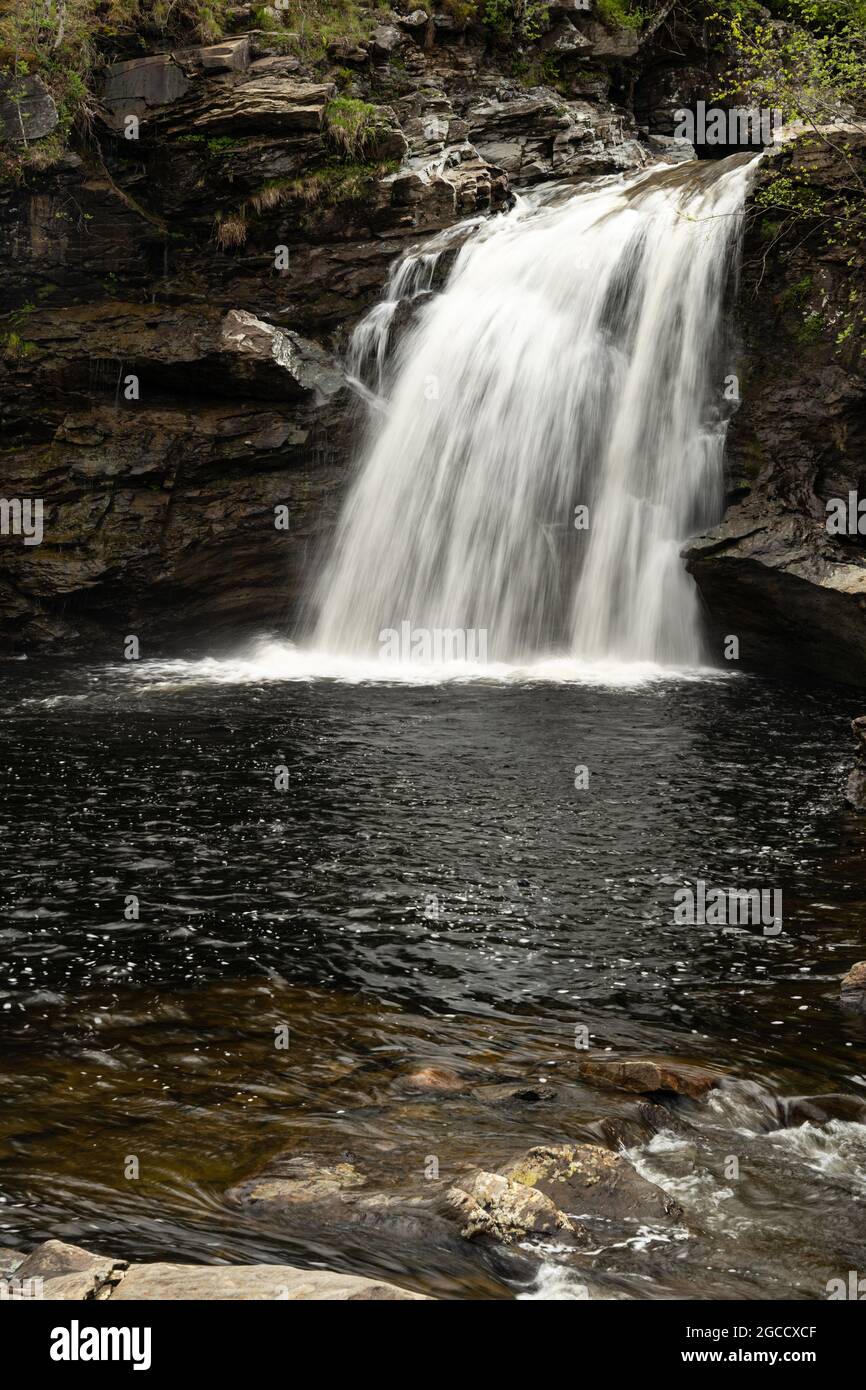 Cascade coulant sur des rebords rocheux dans un bassin sombre sur l'île écossaise Banque D'Images