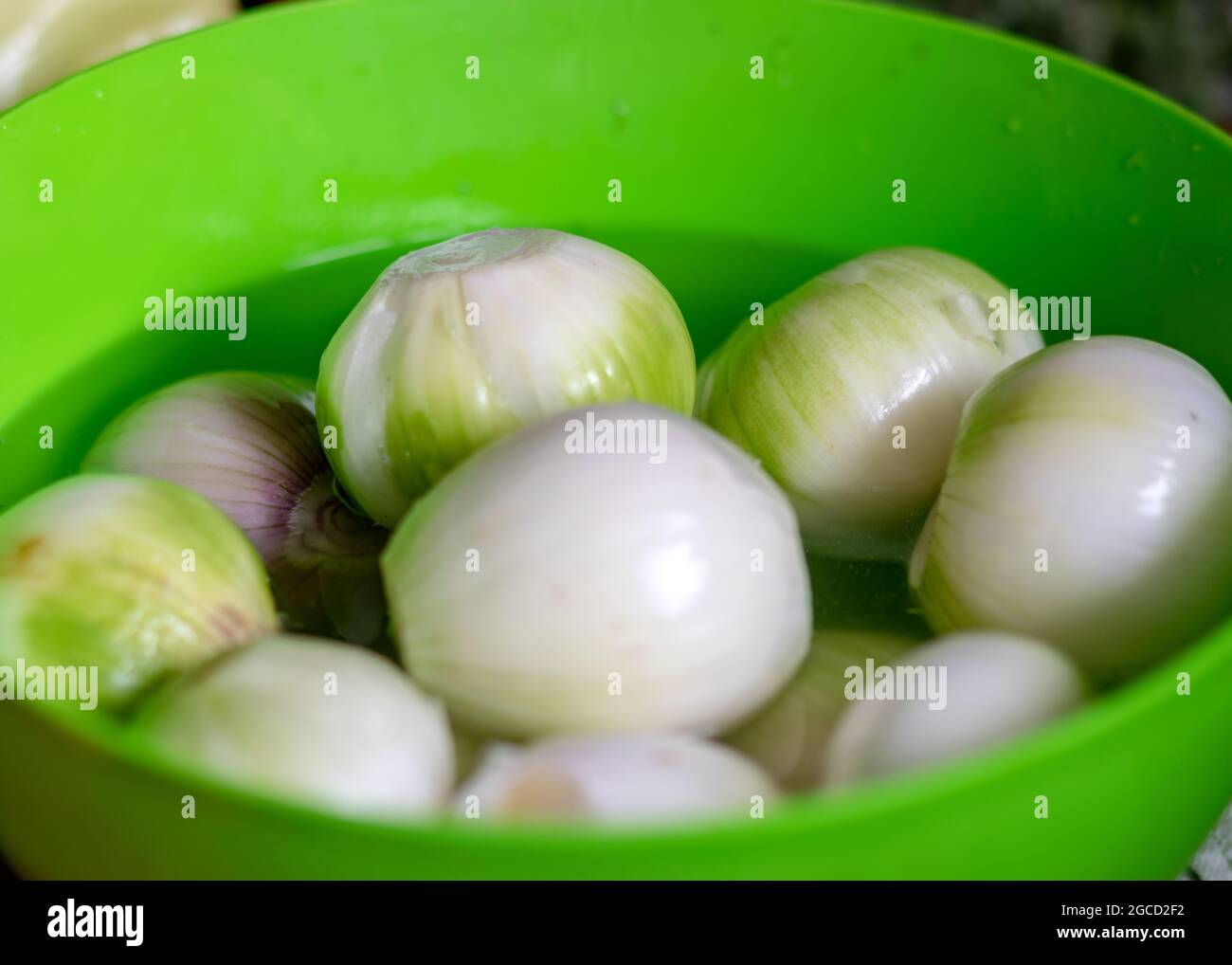 photo en couleur avec oignons pelés dans un bol vert, oignons préparés pour la conservation à la maison, temps de récolte d'automne Banque D'Images