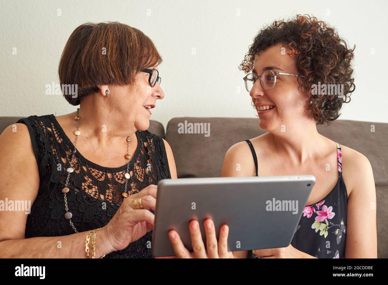 La femme âgée est heureuse d'apprendre à utiliser les réseaux sociaux tandis que la jeune fille explique comment utiliser la tablette Banque D'Images