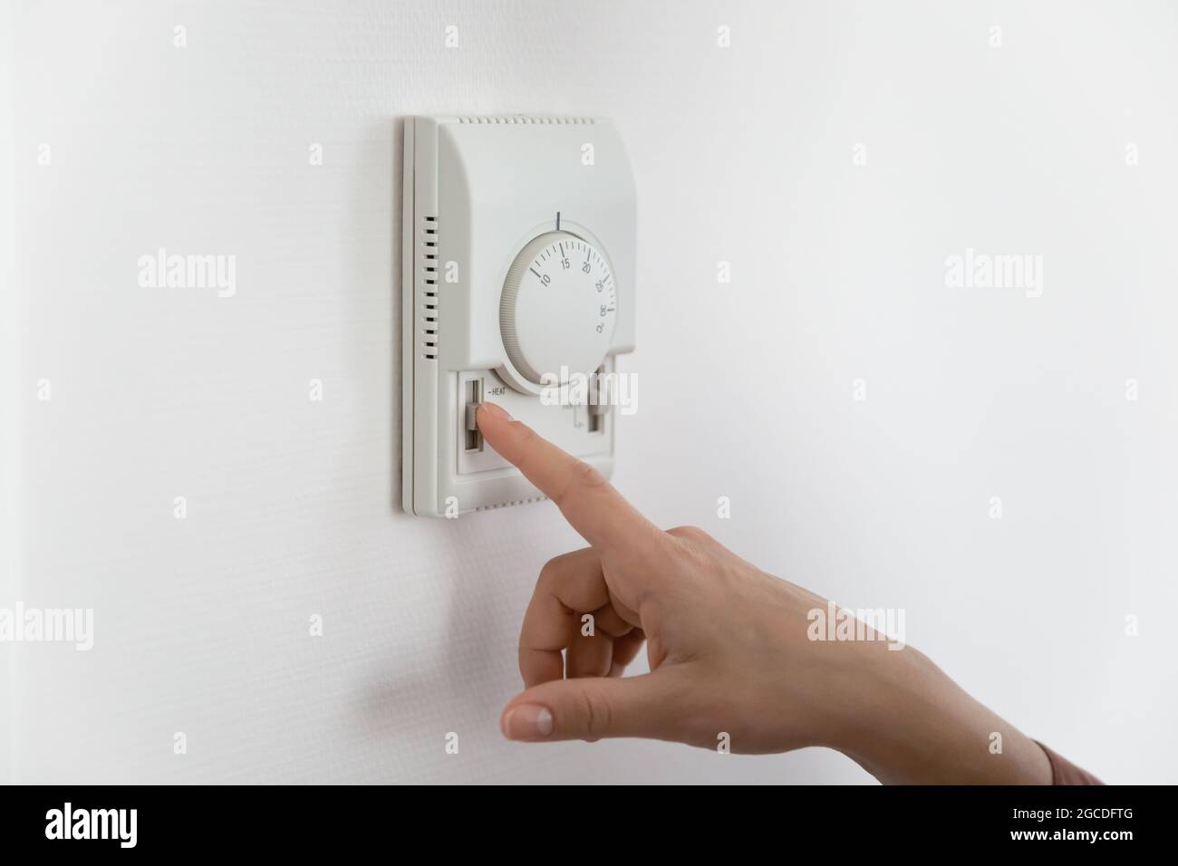 Gros plan de la femme régler la température sur le climatiseur Banque D'Images