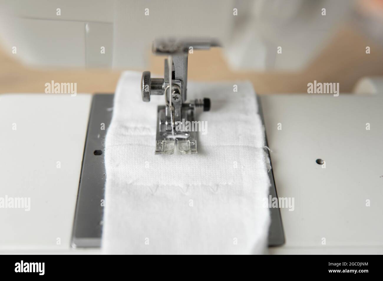 Machine à coudre avec un chiffon blanc sur une table en bois. Banque D'Images
