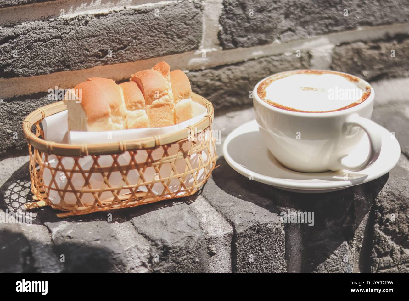 Cappuccino et toast dans le panier avec lumière du matin. Petit déjeuner. Banque D'Images