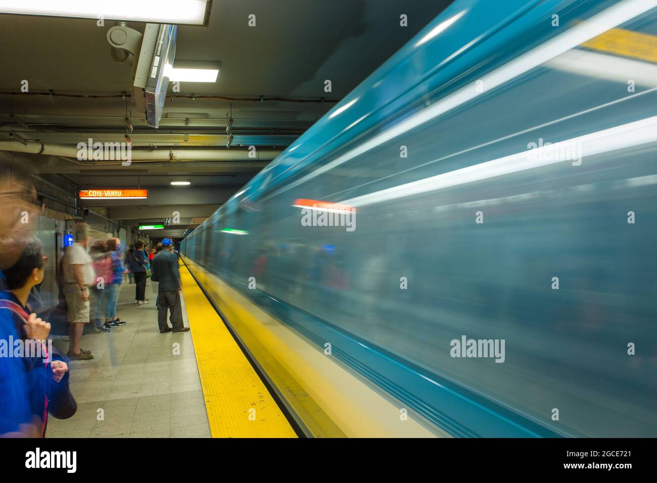 Un train de métro passe à côté tandis que les gens attendent. Le métro de Montréal (Métro de Montréal) est un métro à bandage caoutchouc, à Montréal (Québec) Banque D'Images