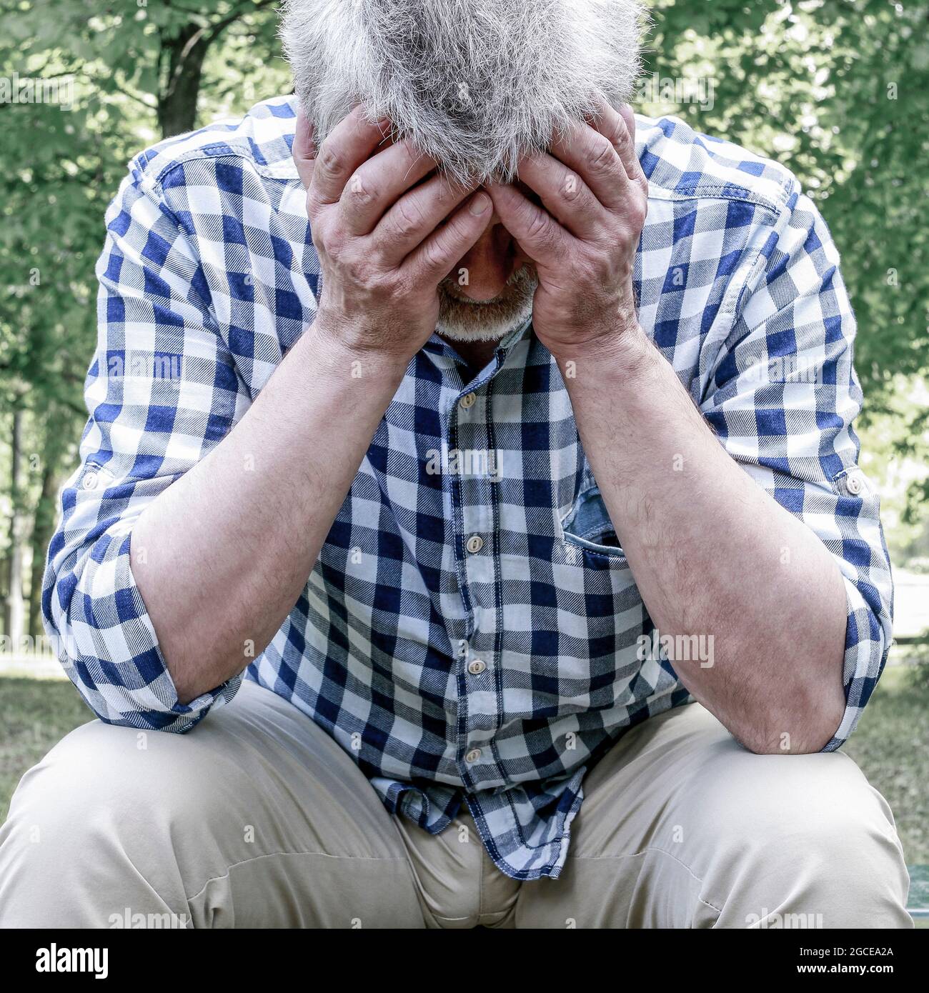 Vieux déprimé assis sur le banc dans un parc. Banque D'Images
