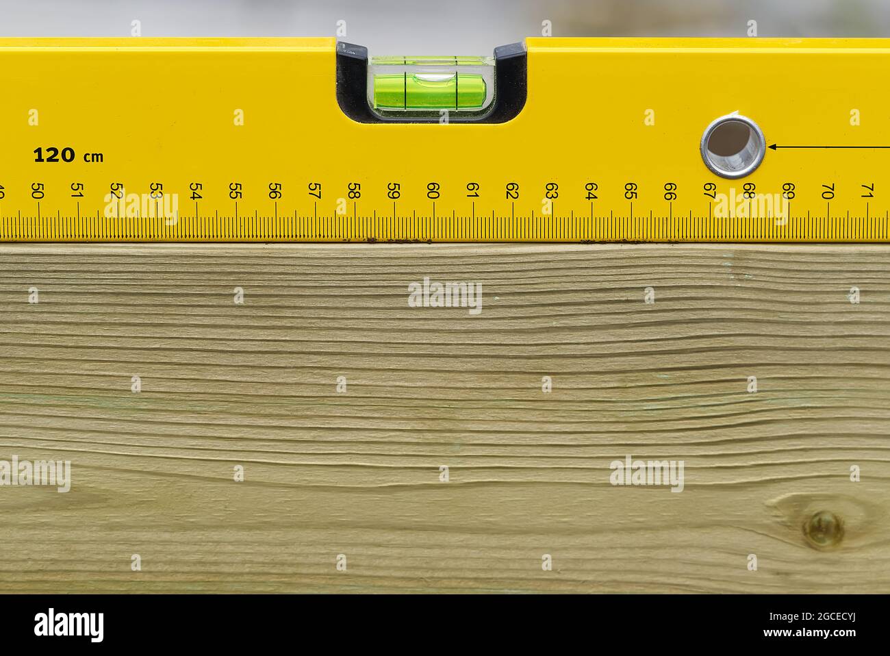 Niveau à bulle jaune horizontal sur panneau en bois. Outil de mesure pour ouvriers de construction sur poutre en bois. Banque D'Images