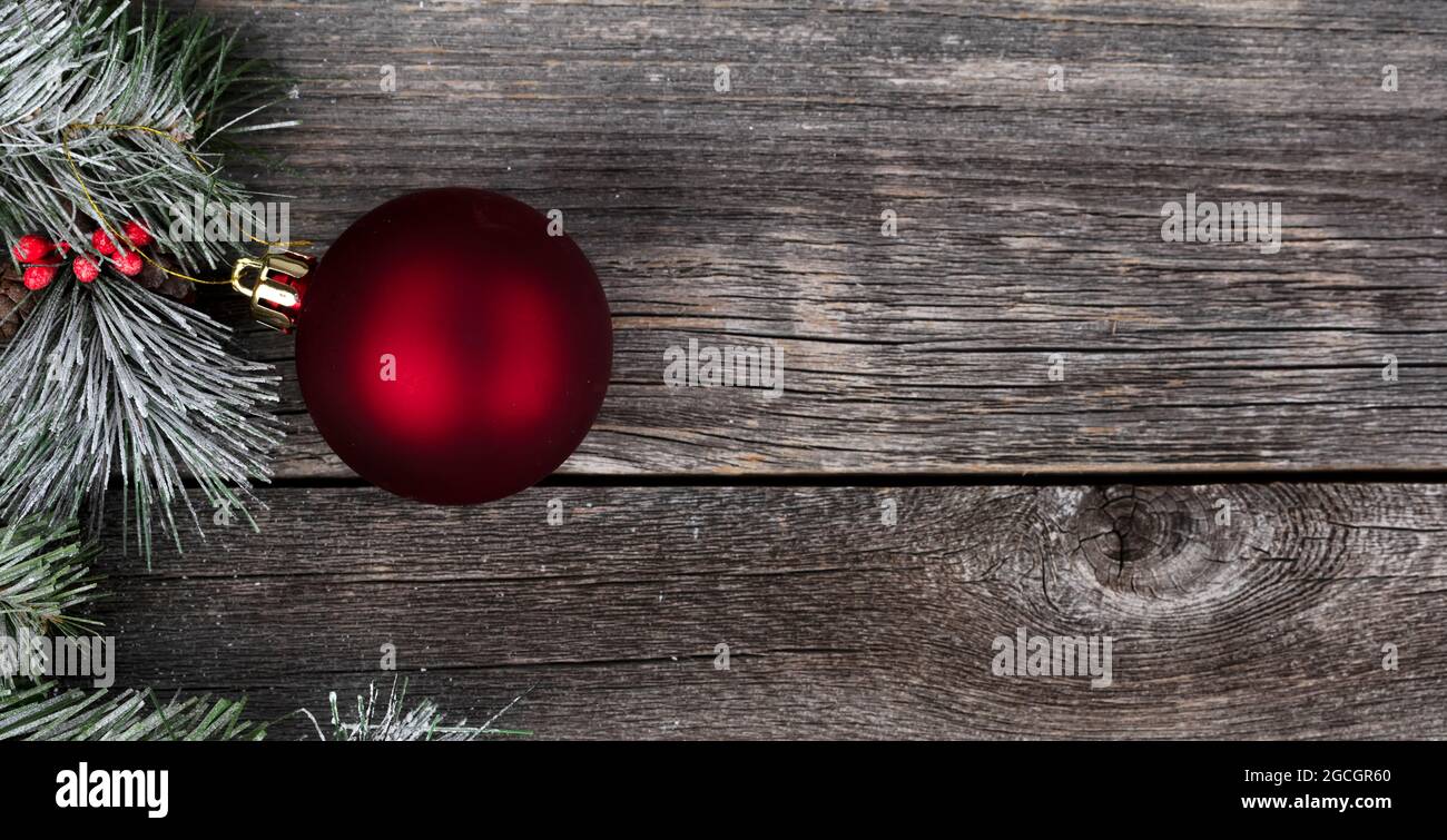Gros plan sur un seul ornement de boule rouge avec des branches de sapin de neige givré et un fond en bois pour un joyeux Noël ou un concept de fête du nouvel an heureux Banque D'Images
