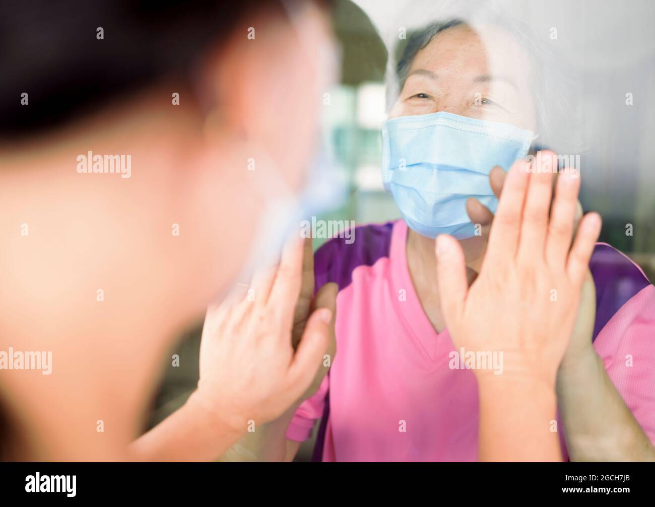 La femme âgée en masque médical communique avec sa fille par la fenêtre. Personnes âgées en quarantaine, isolées. Coronavirus pandémique covid-19 Banque D'Images