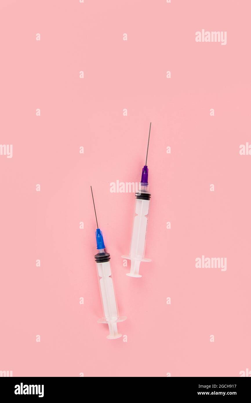 Seringues placées sur fond rose. Concept médical et vaccination. Vue de dessus, plat, espace de copie Banque D'Images