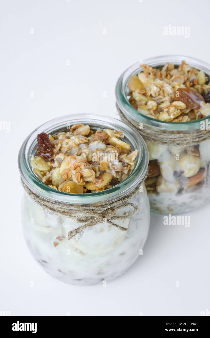 Petit déjeuner sain. Flocons d'avoine Granola au yaourt grec et aux noix muesli à la banane en pots sur fond clair. Végétalien, végétarien et régime de perte de poids Banque D'Images