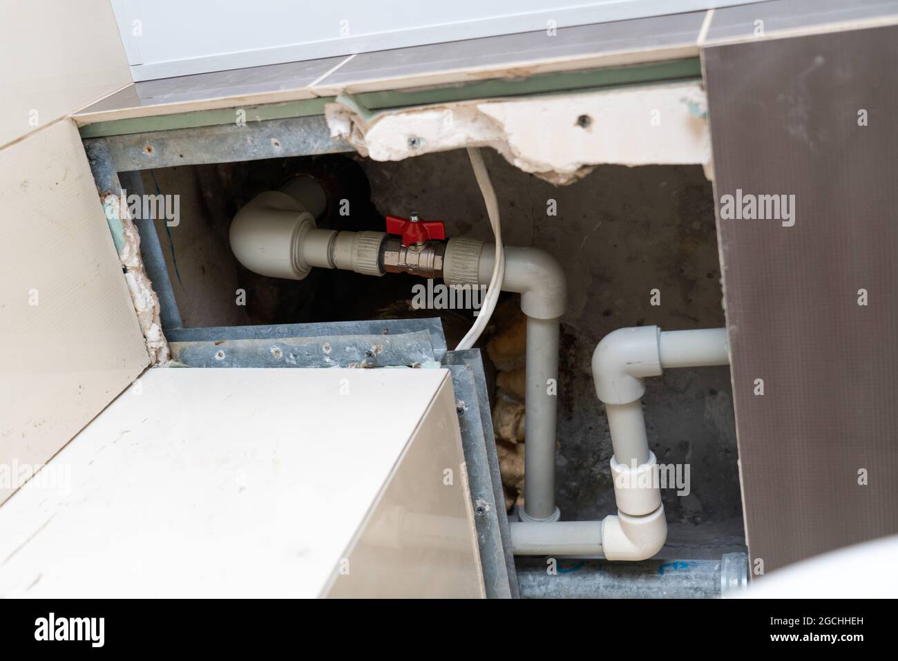 tuyau en plastique souple dans la trappe du plafond. remplacement de la colonne montante et des tuyaux à travers les carreaux coupés dans le plafond. Clapet à bille rouge sur un PEX-al Banque D'Images