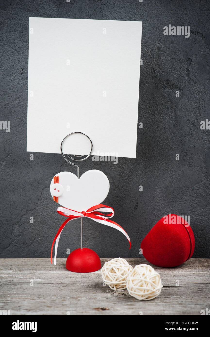 Porte-photo avec carte vierge et boîte cœur rouge sur fond de béton. Place pour la photo ou le texte Banque D'Images