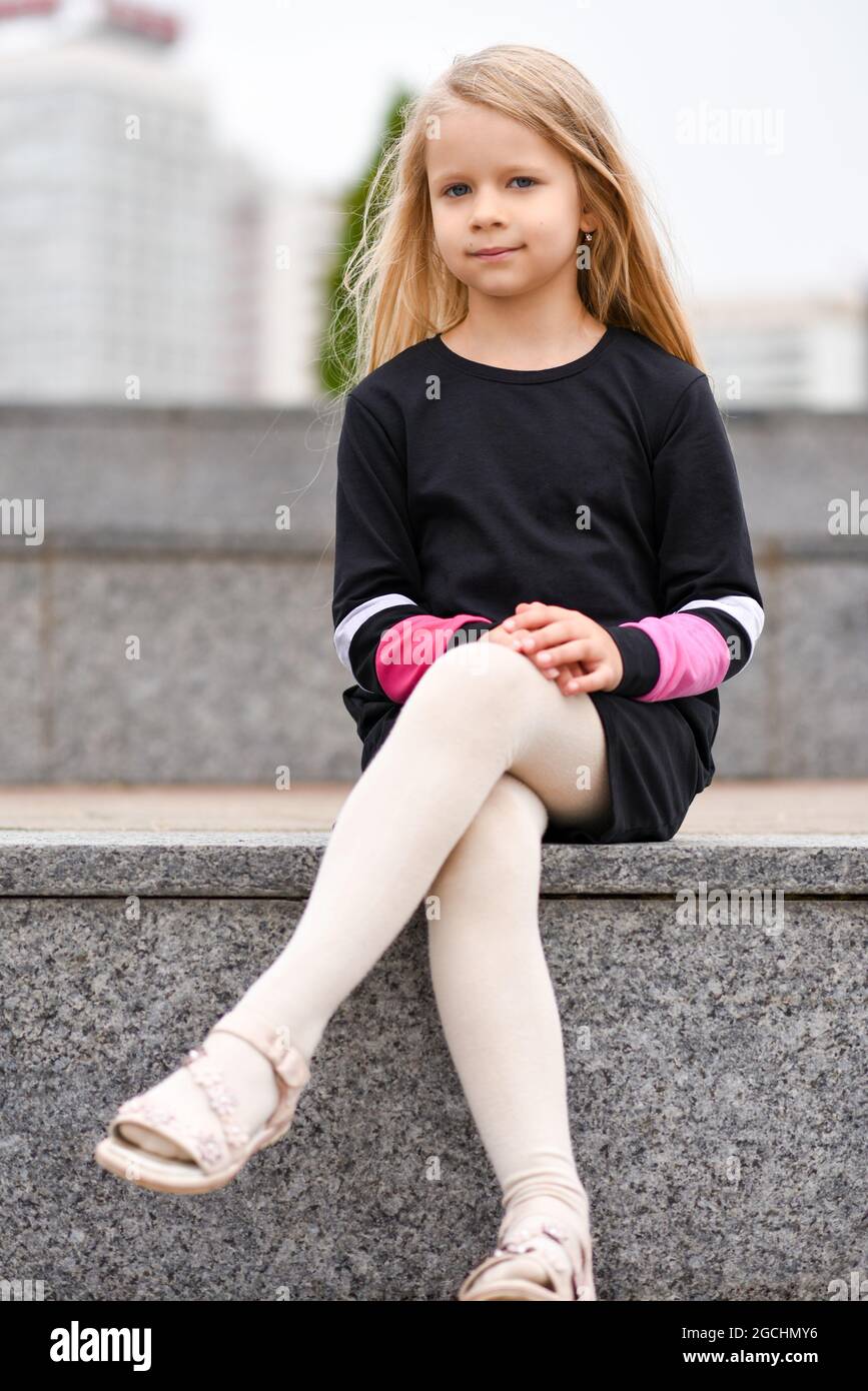 Petite fille dans une robe noire est assis sur un banc Photo Stock - Alamy