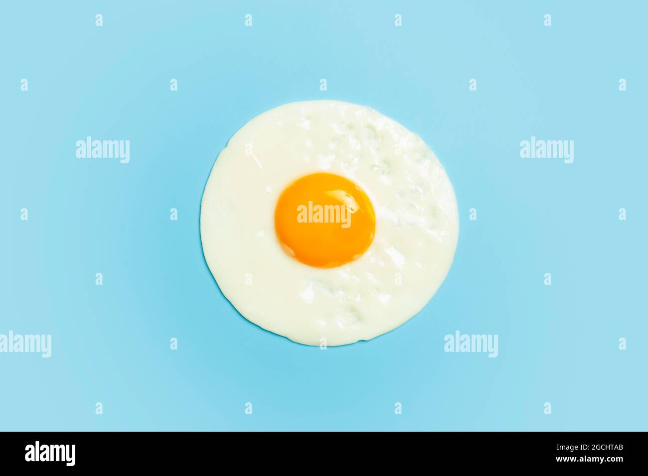 L'œuf frit est minime. Œuf plat sur un fond blanc bleu clair. Petit déjeuner créatif et idée de nourriture. Photo de haute qualité Banque D'Images