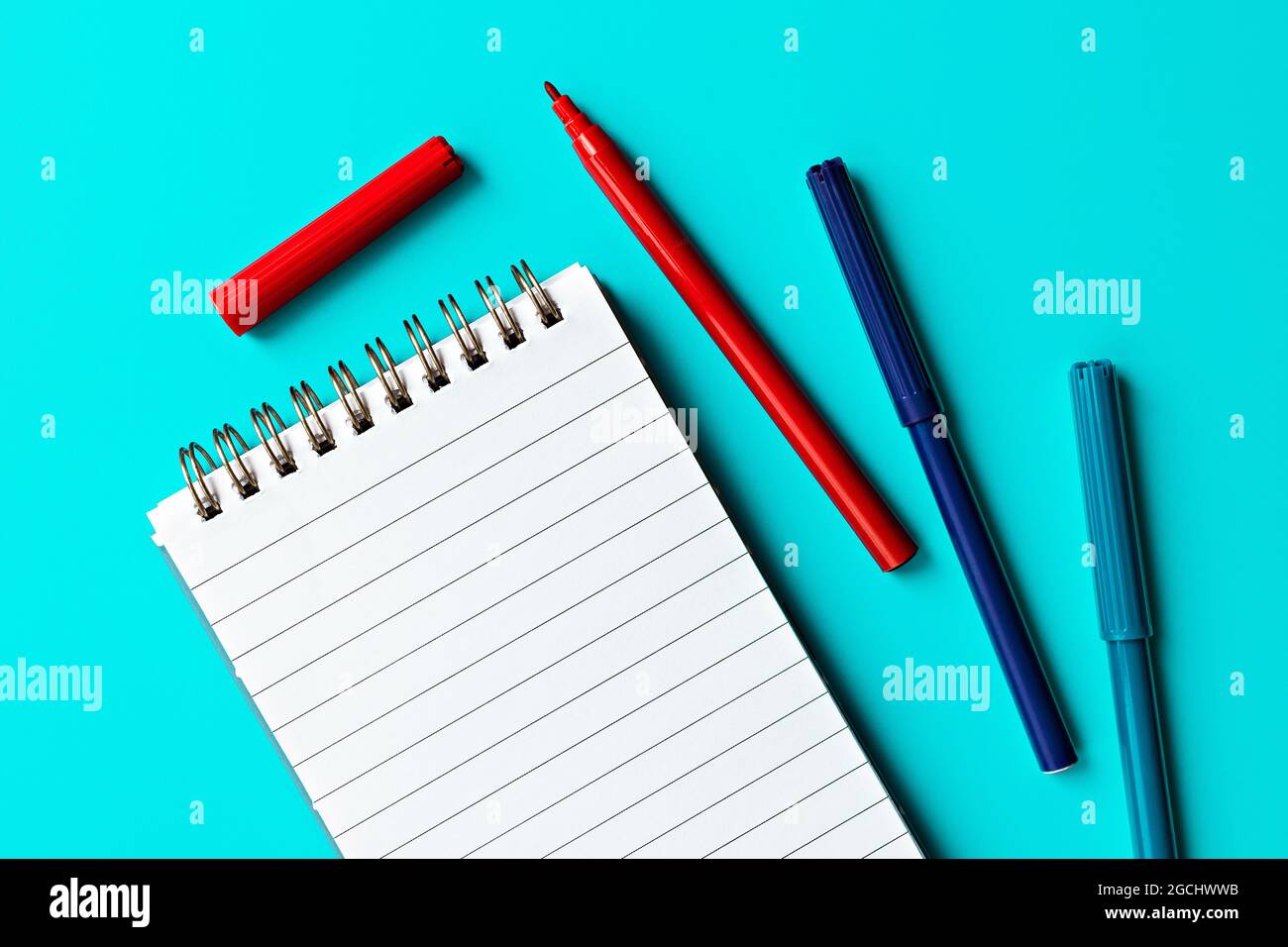 bloc-notes blanc vide et marqueurs multicolores sur fond turquoise. modèle pour le texte et le design Banque D'Images