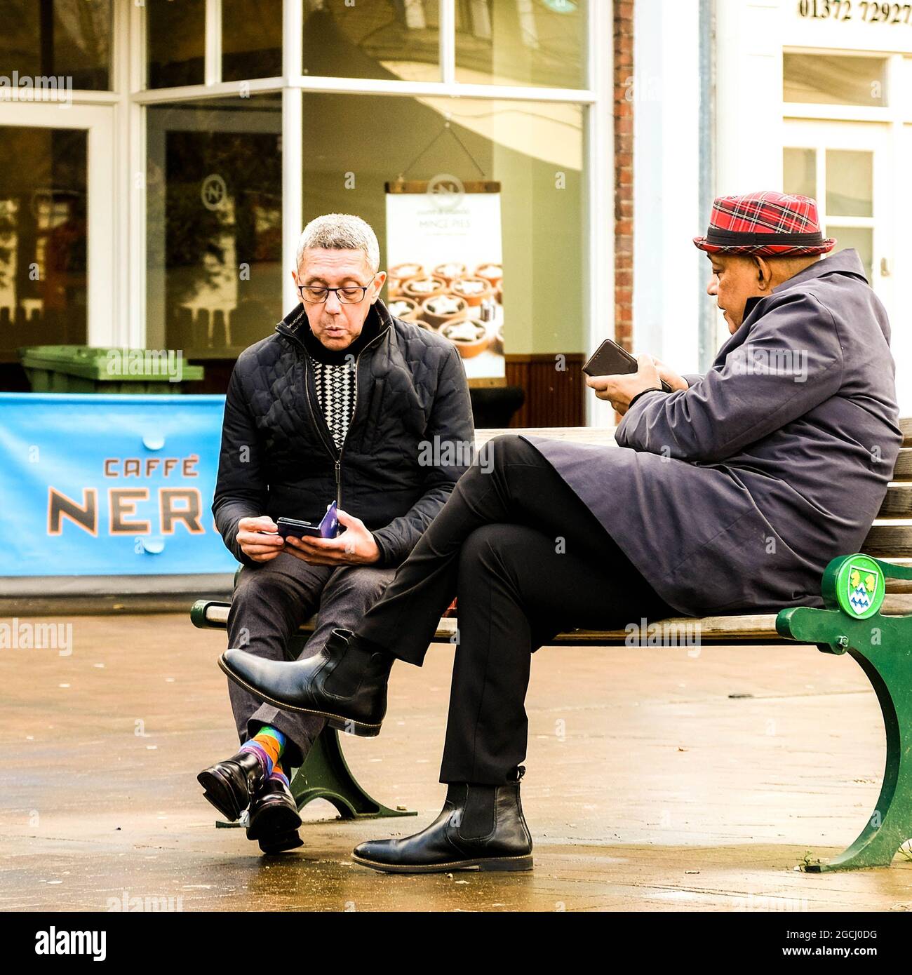 Décembre 2020, Epsom Surrey, Londres, Royaume-Uni, deux hommes senior amis assis Banc parlant Vérification des messages téléphoniques Banque D'Images