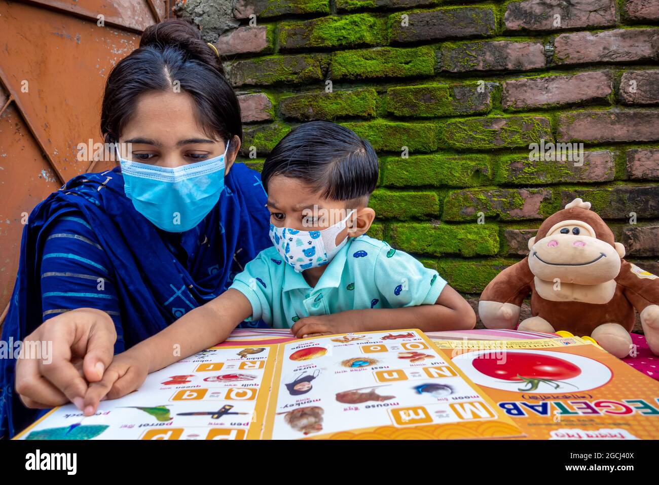 Dans le confinement et la mise en quarantaine à domicile de l'épidémie de Covid-19, une mère asiatique enseigne à son enfant à la maison portant un masque à Joypara, Dohar, Dhaka, B Banque D'Images