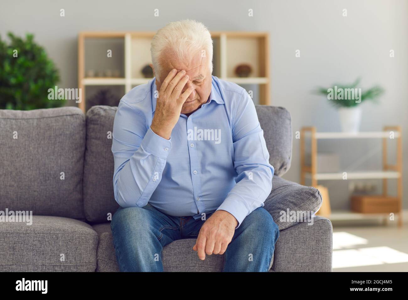 Homme âgé assis sur un canapé, se plaignant de la perte de sa femme ou souffrant de mauvais maux de tête Banque D'Images
