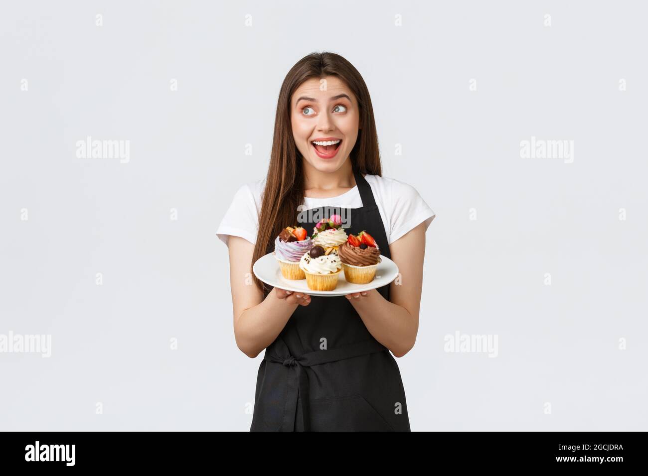 Concept des employés d'épicerie, des petites entreprises et des cafés. Une serveuse souriante et sympathique apporte des desserts au café. Un joli barista souriant Banque D'Images