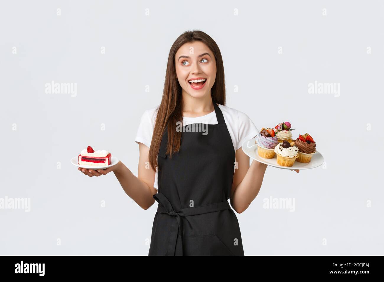 Concept des employés d'épicerie, des petites entreprises et des cafés. Serveuse souriante et sympathique dans un café, avec des assiettes et des petits gâteaux et un café, servant Banque D'Images