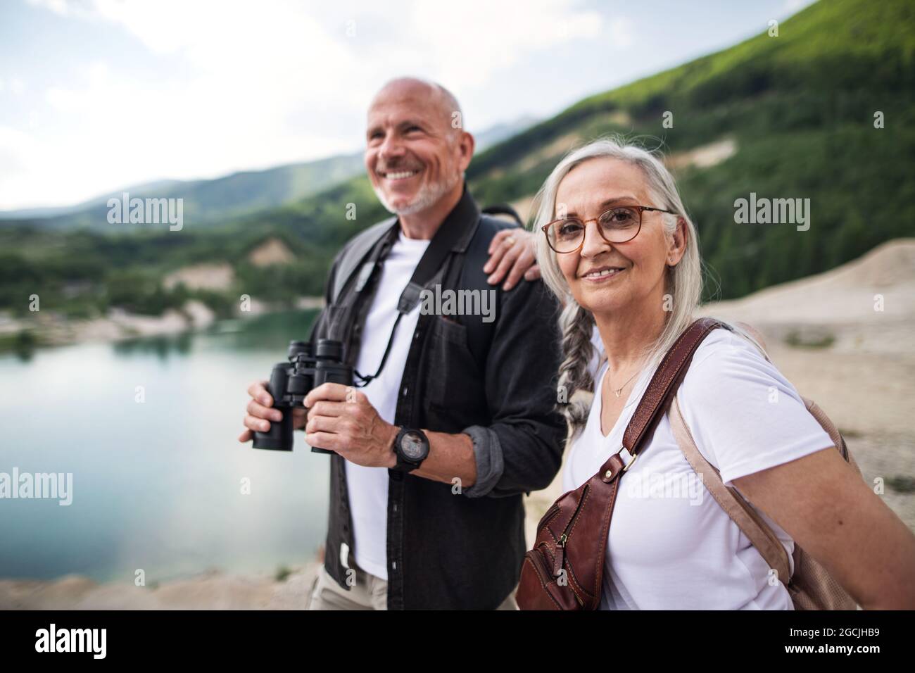 Joyeux couple senior sur une randonnée les vacances d'été, en utilisant des jumelles. Banque D'Images