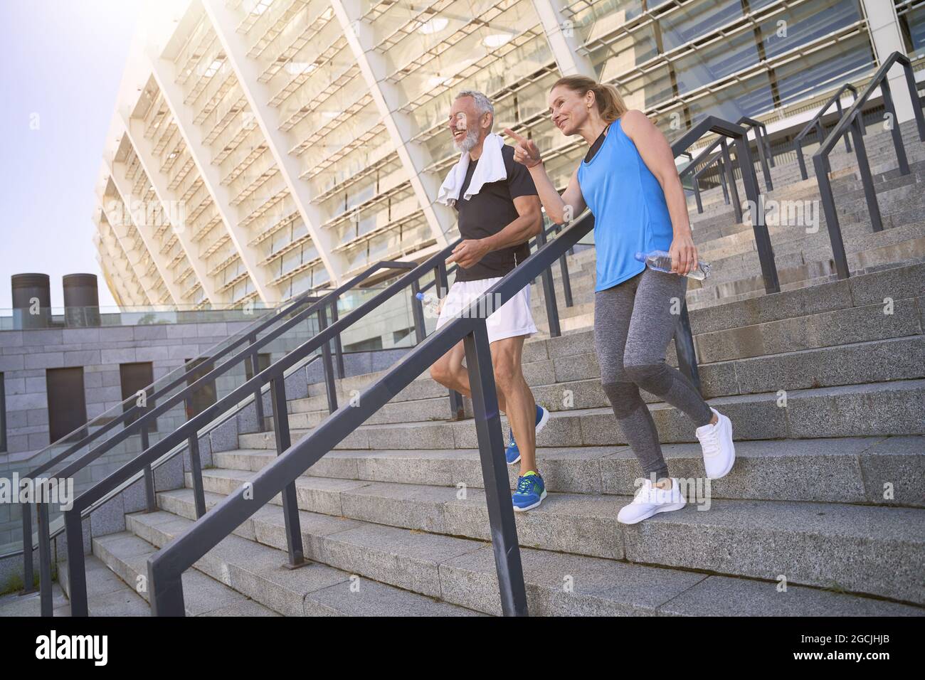 Couple d'âge moyen, homme et femme dans les vêtements de sport marchant dans les escaliers après s'exercer ensemble à l'extérieur Banque D'Images