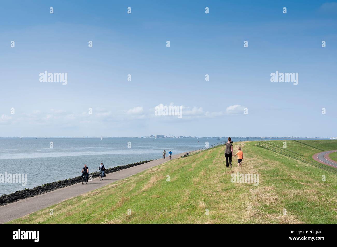 en été, les gens marchent à vélo sur la digue près d'oudeschild, sur l'île hollandaise de texel, sous le ciel bleu Banque D'Images
