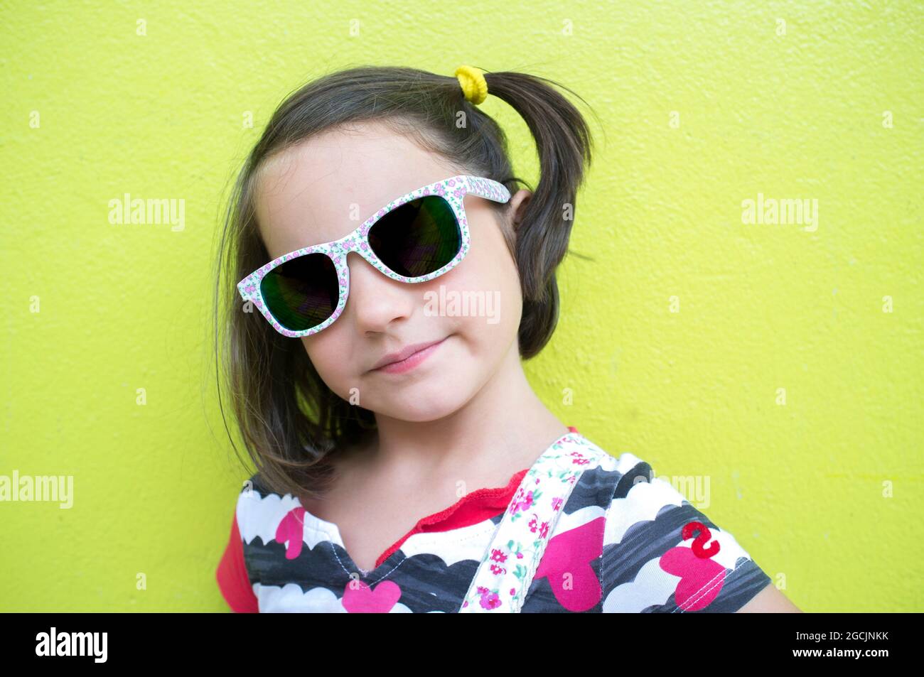 petite fille de 6 ans avec des lunettes de soleil de mode foncées sur fond  vert. Enfants yeux santé concept Photo Stock - Alamy