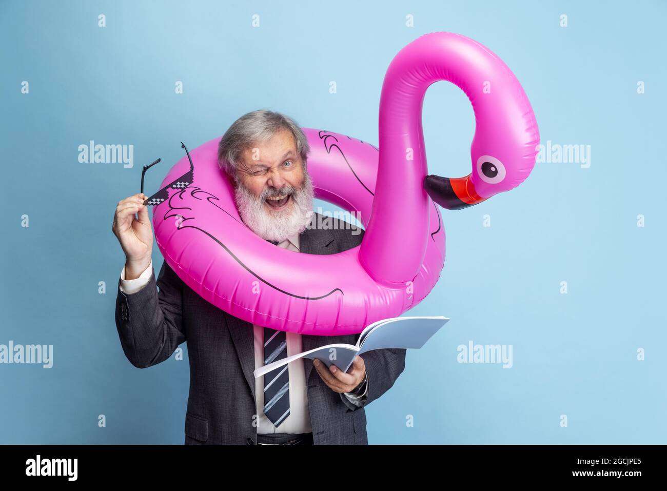 Portrait de l'homme à tête grise aîné, professeur, enseignant travaillant isolé sur fond bleu de studio. Concept de profession professionnelle, emploi, éducation Banque D'Images