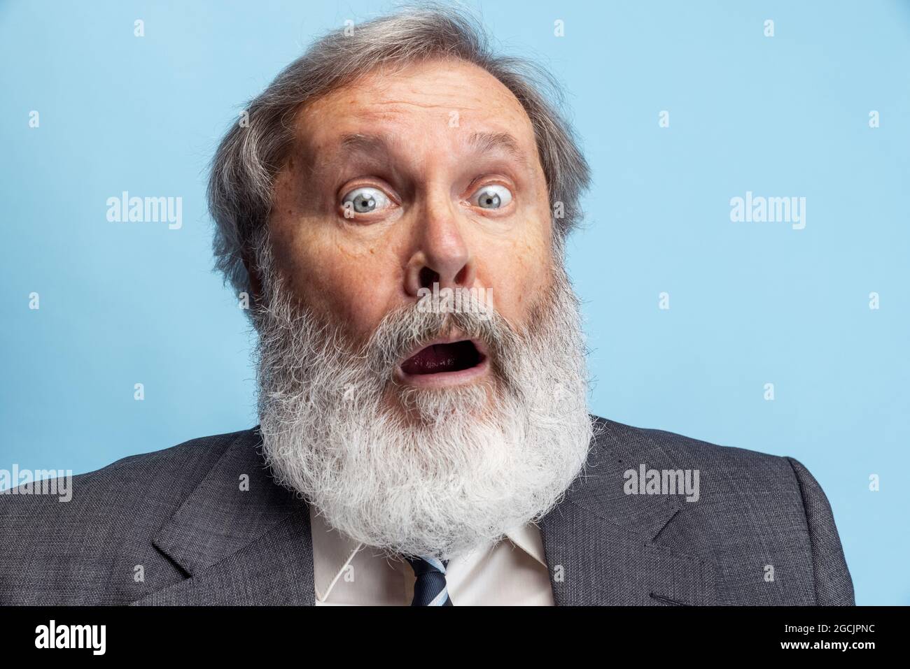 Un professeur fou, un professeur, un homme barbu à tête grise qui se pose isolé sur fond de studio gris. Concept de profession professionnelle, emploi, éducation, drôle Banque D'Images