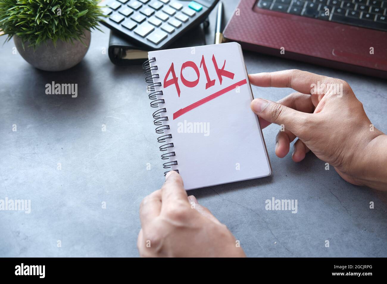 Tenez le bloc-notes avec Word 401k et l'ordinateur portable sur la table Banque D'Images