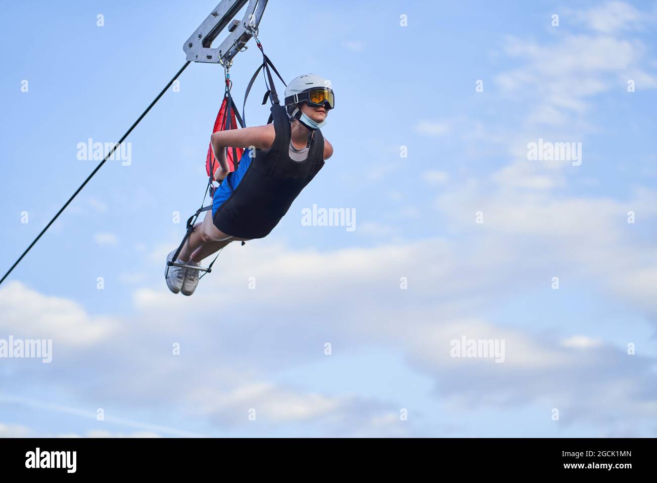 Anonyme femme courageuse dans l'équipement de sécurité à cheval tyrolienne au-dessus des montagnes en été Banque D'Images