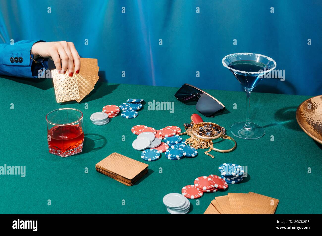Rognez une femelle méconnaissable avec des cartes et des jetons jouant au poker tout en étant assis à la table verte Banque D'Images